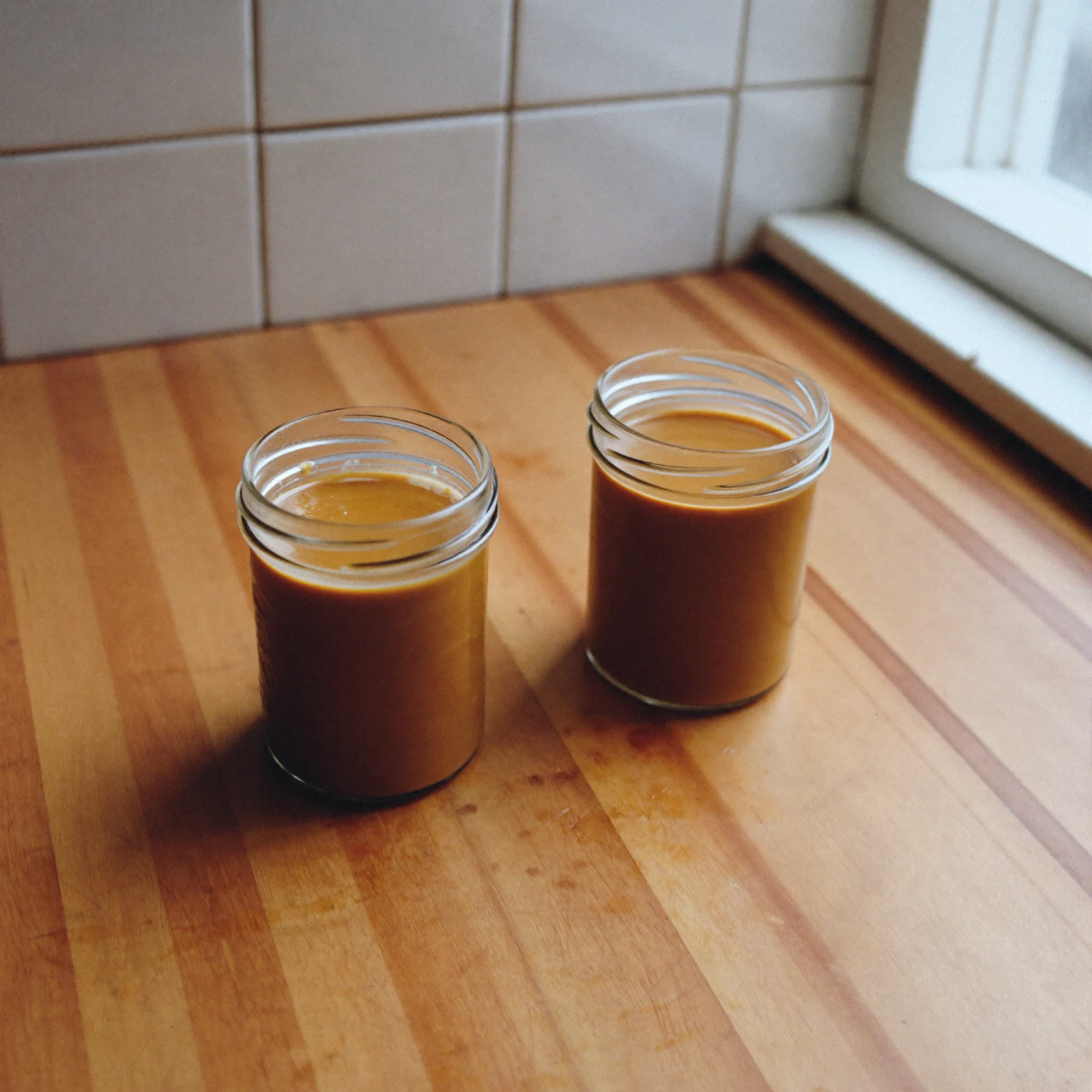 Two open jars of almond butter side by side on a kitchen counter