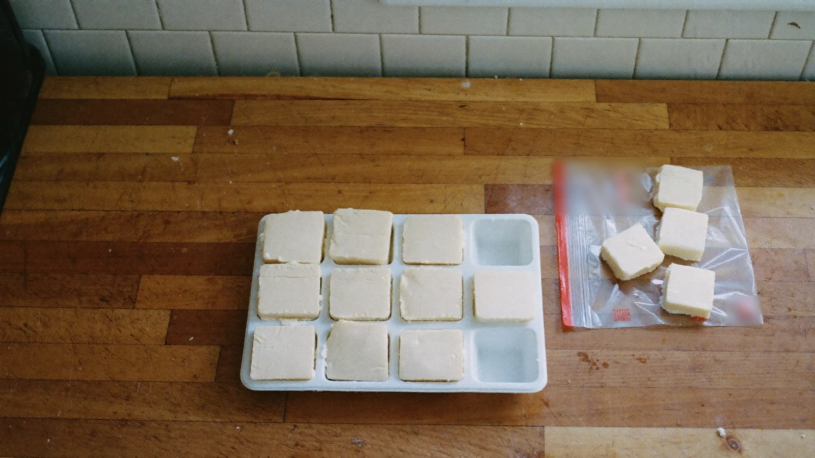 Cubes of frozen bacon grease from an ice cube tray going into a freezer bag