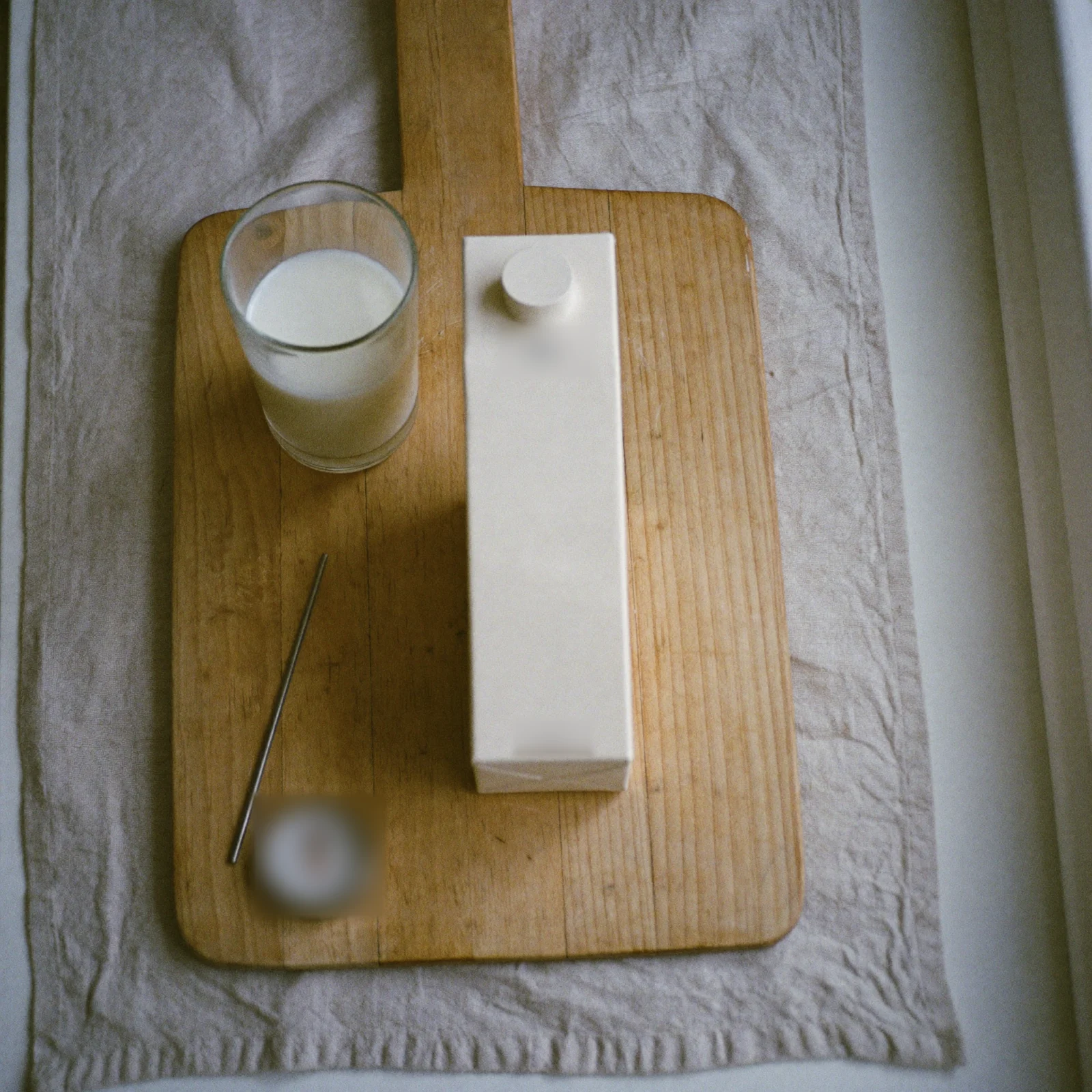 How to store milk - A plain carton of milk and a glass of milk on a beech-wood board beside a dial thermometer