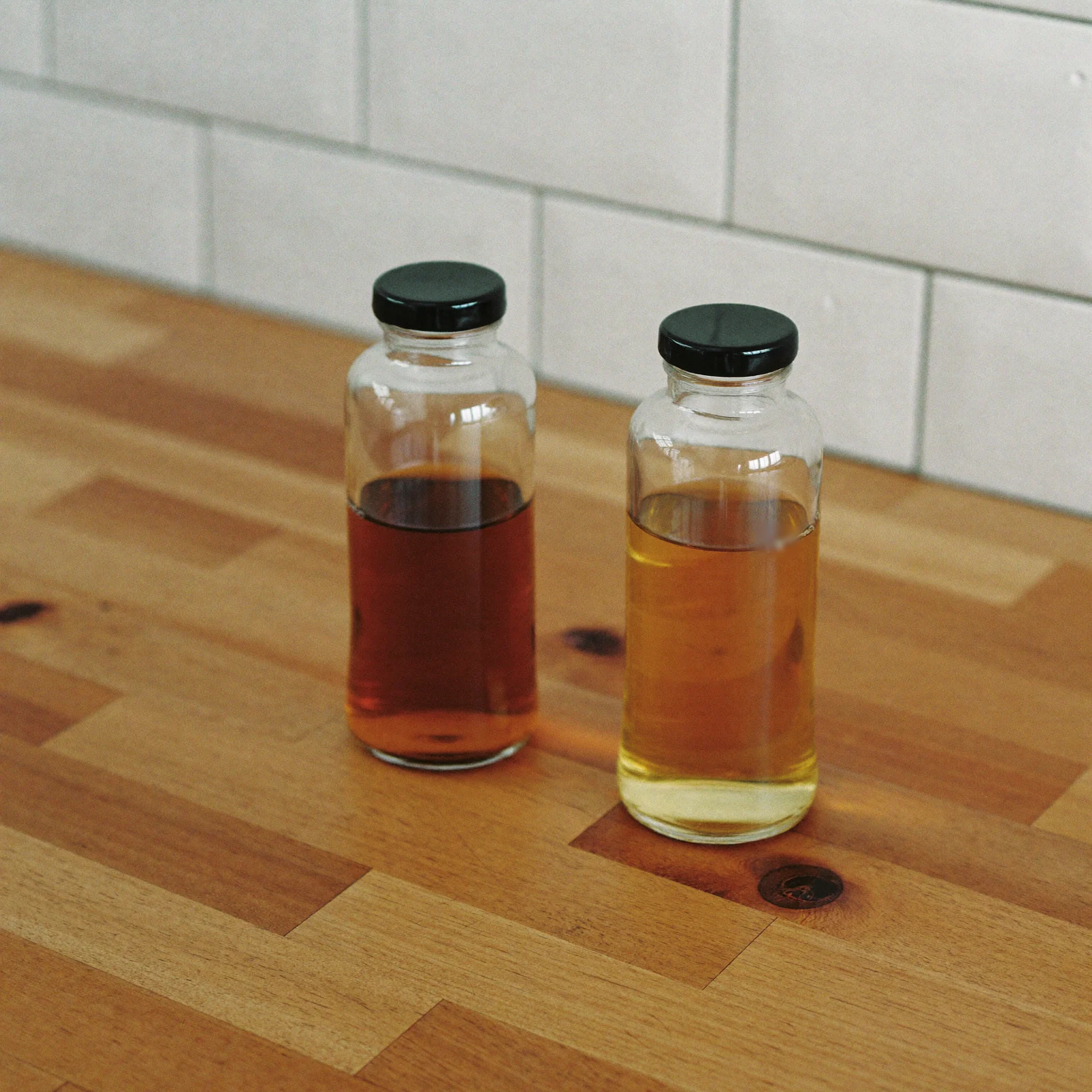 An older, paler bottle of imitation vanilla beside a darker fresh one