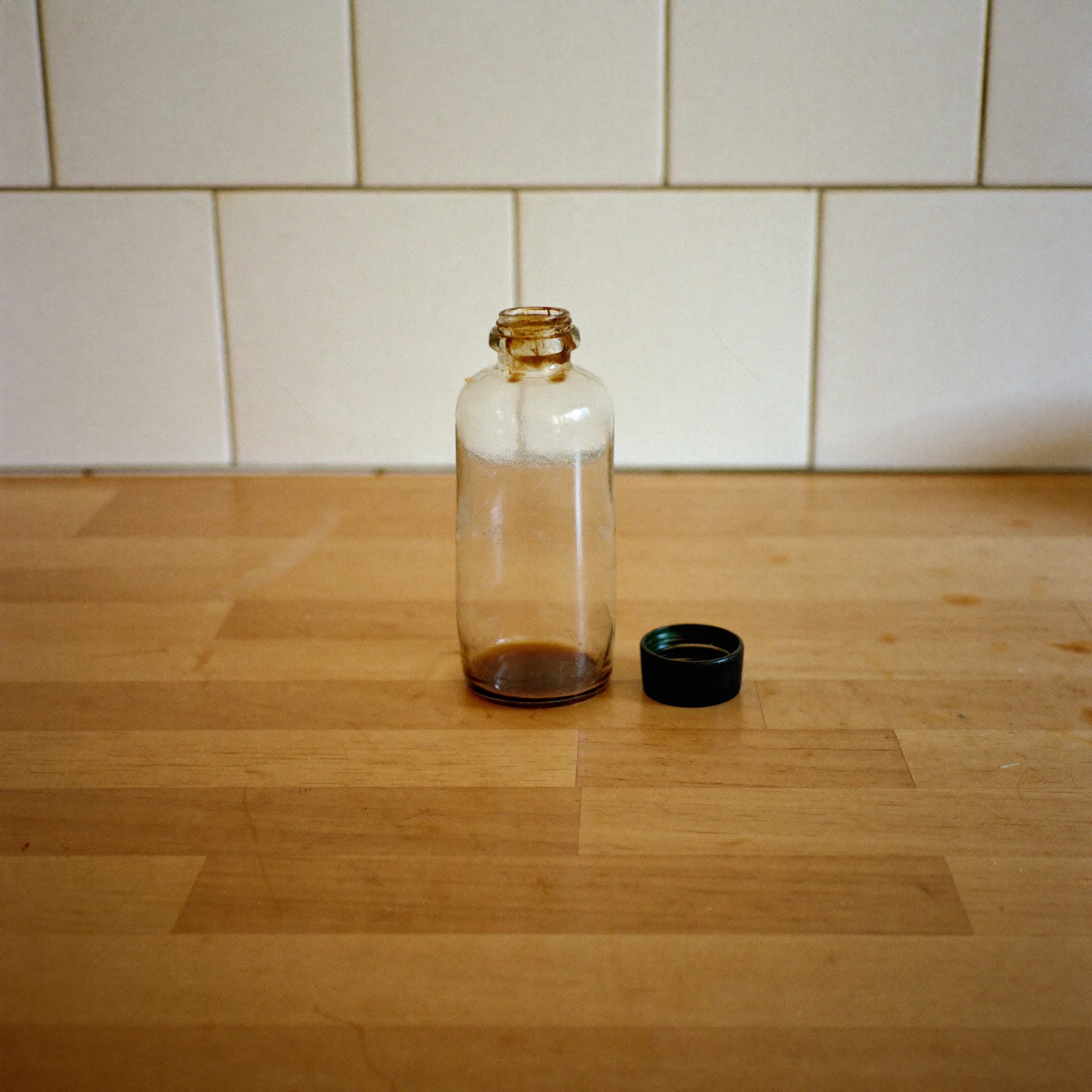 A nearly empty bottle of imitation vanilla with a sticky, crusted neck