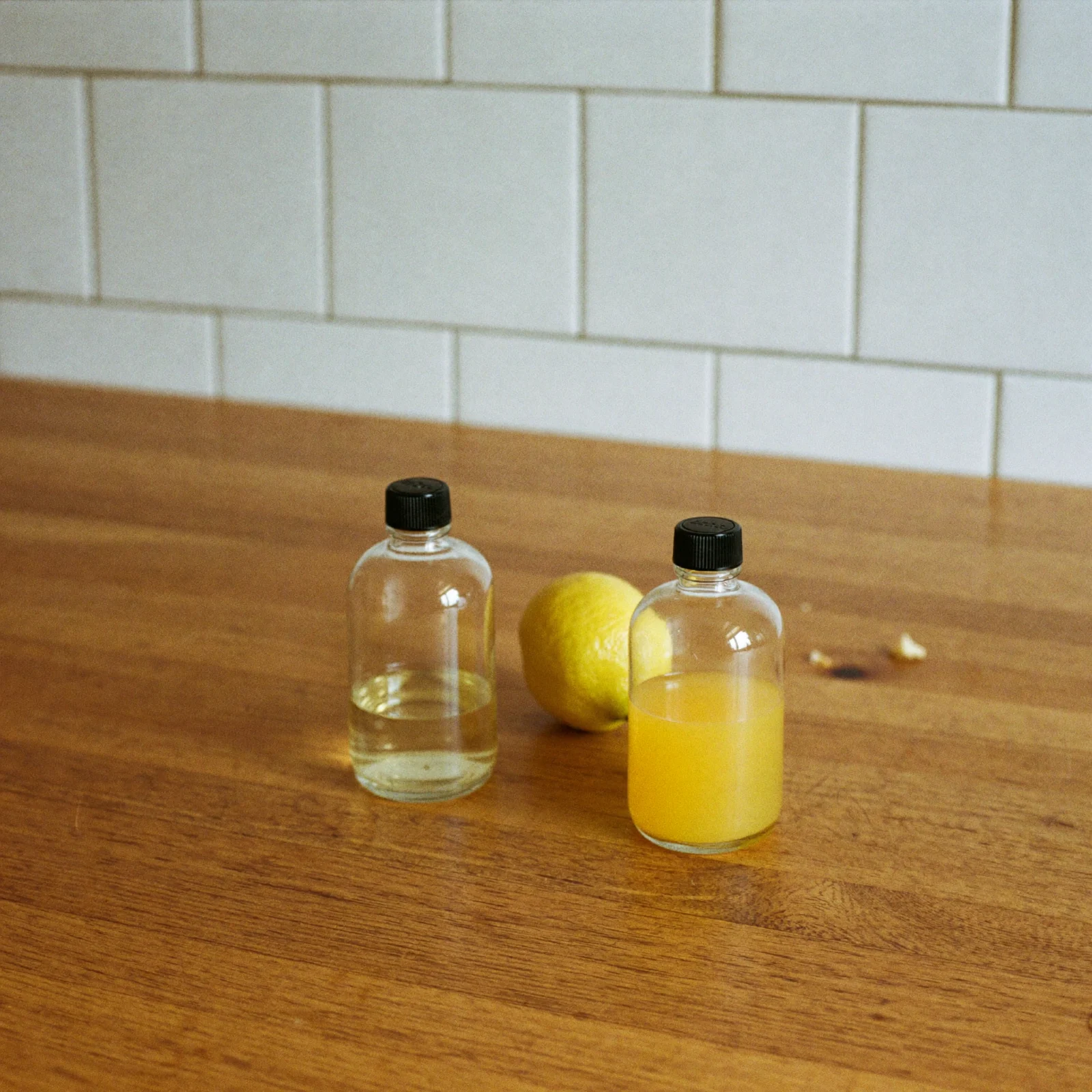 Two bottles of lemon extract side by side, one pale and clear and one a stronger yellow