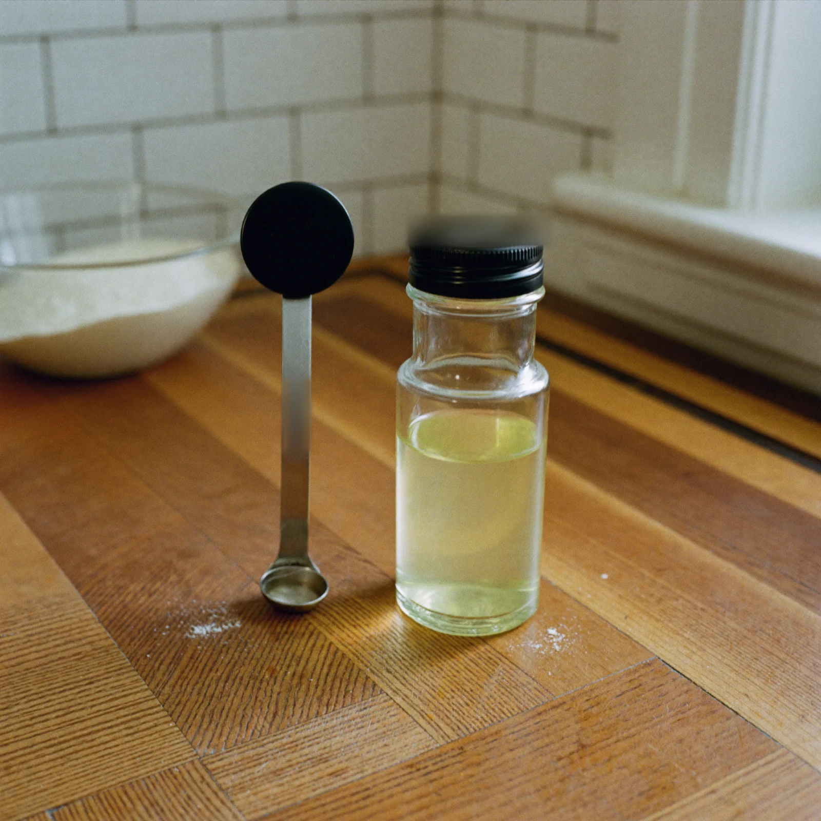 How to store lemon extract: a capped bottle of lemon extract beside a measuring spoon on a kitchen counter