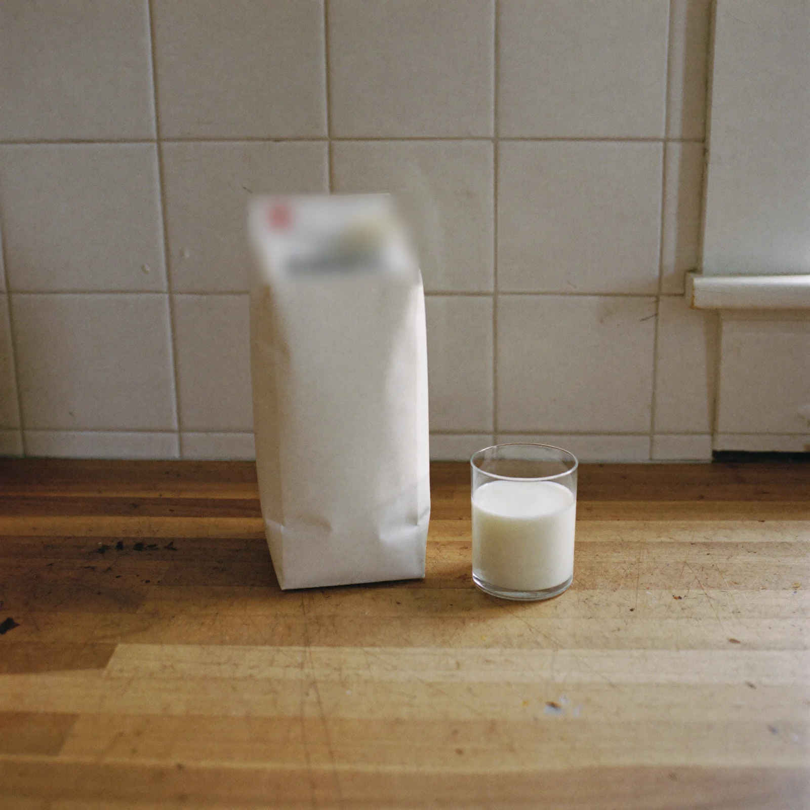 A plain milk carton open beside a glass of milk that still looks ordinary