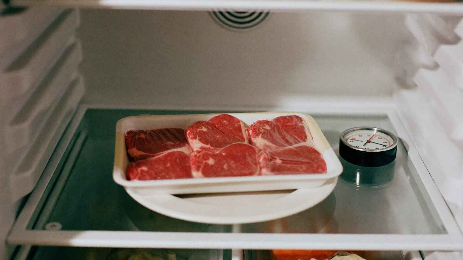 Store steak in its package on a plate on a fridge shelf