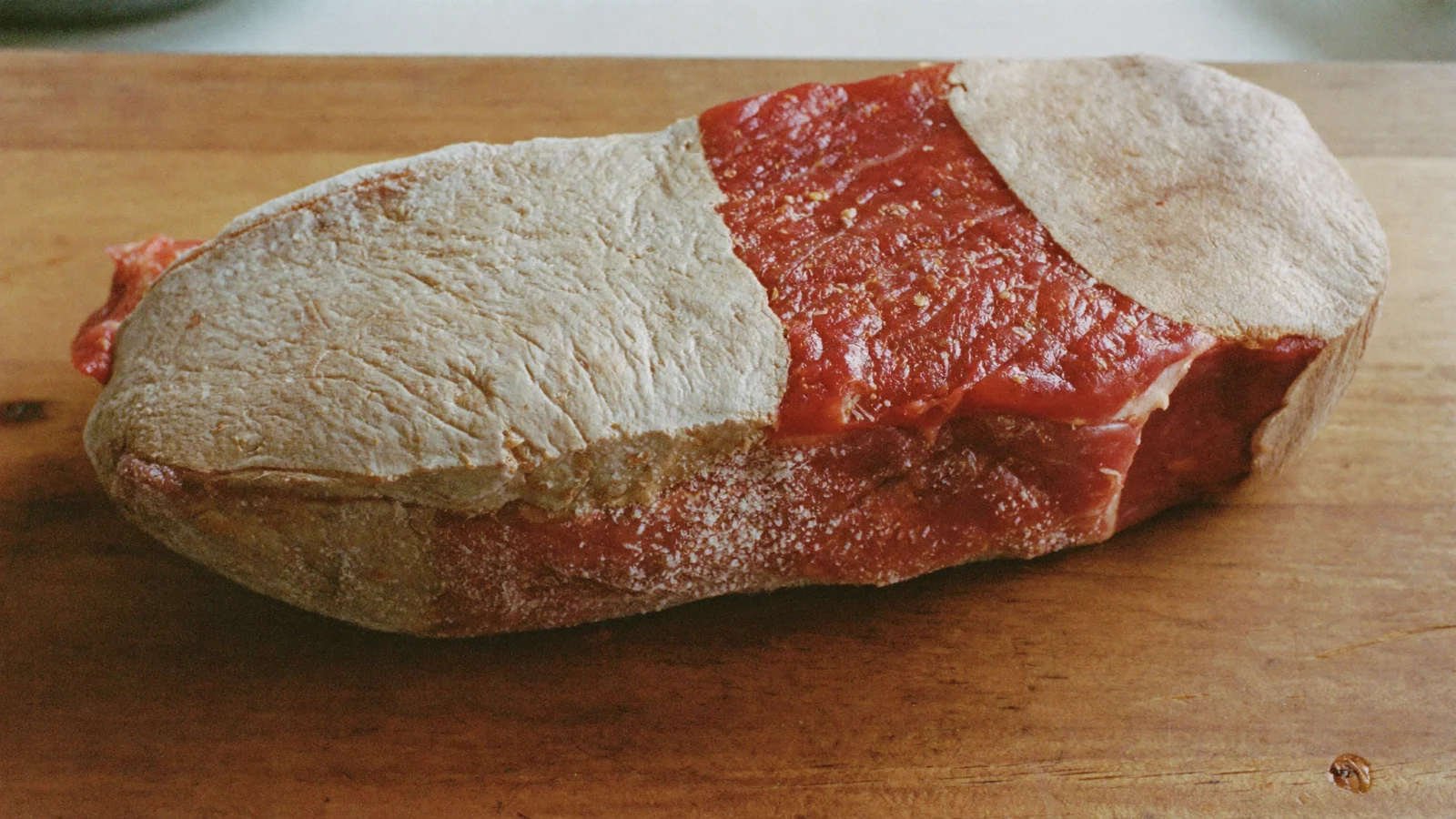 A frozen steak with dry greyish-brown freezer burn spots