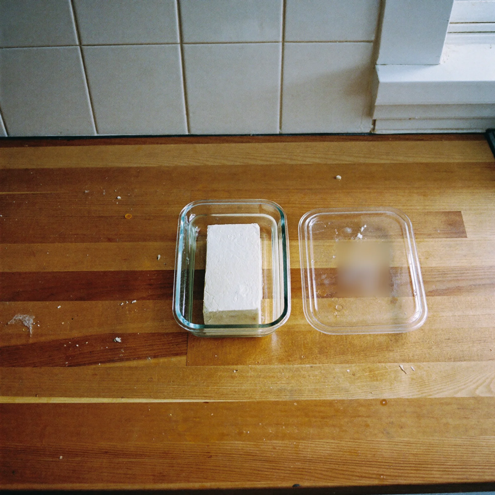 How to store tofu: a block of tofu in a glass container of water with its lid beside it