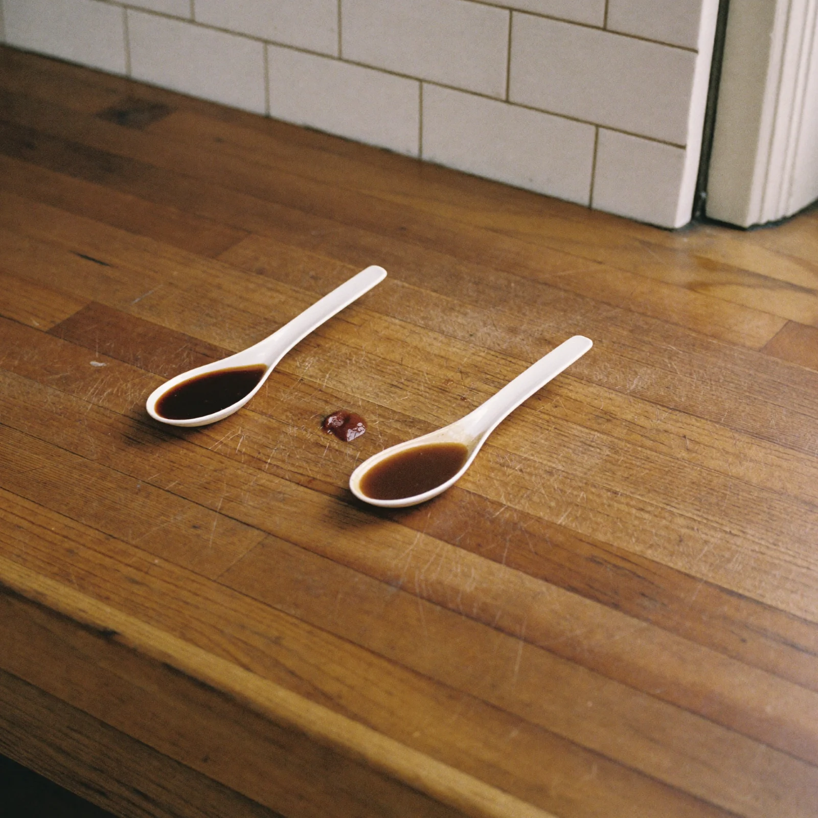 Two spoons of Worcestershire sauce compared, one dark and glossy and one duller and flatter