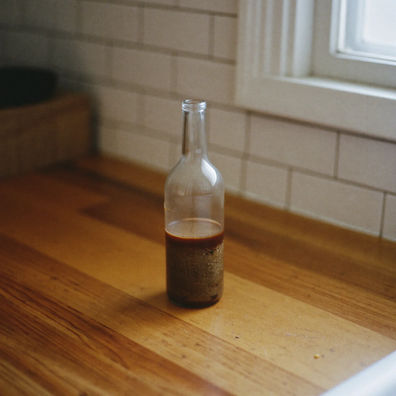 A still bottle of Worcestershire sauce with a darker sludge at the bottom and a thinner layer above it